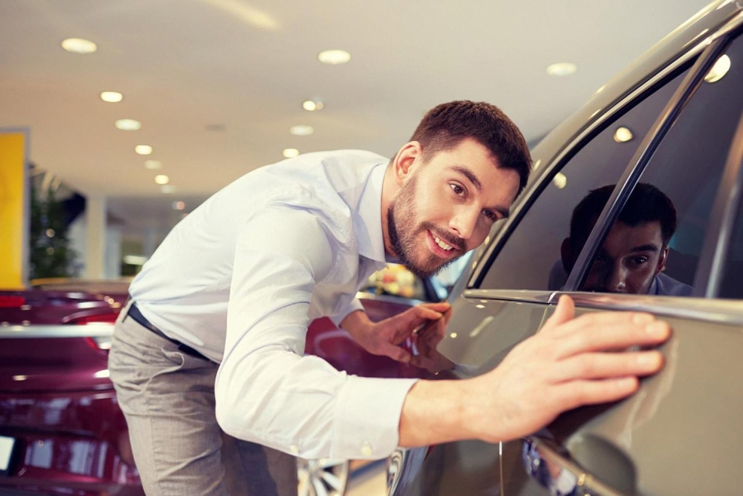 Buyer inspecting a glossy new car finish protected by paint protection film in a UAE showroom