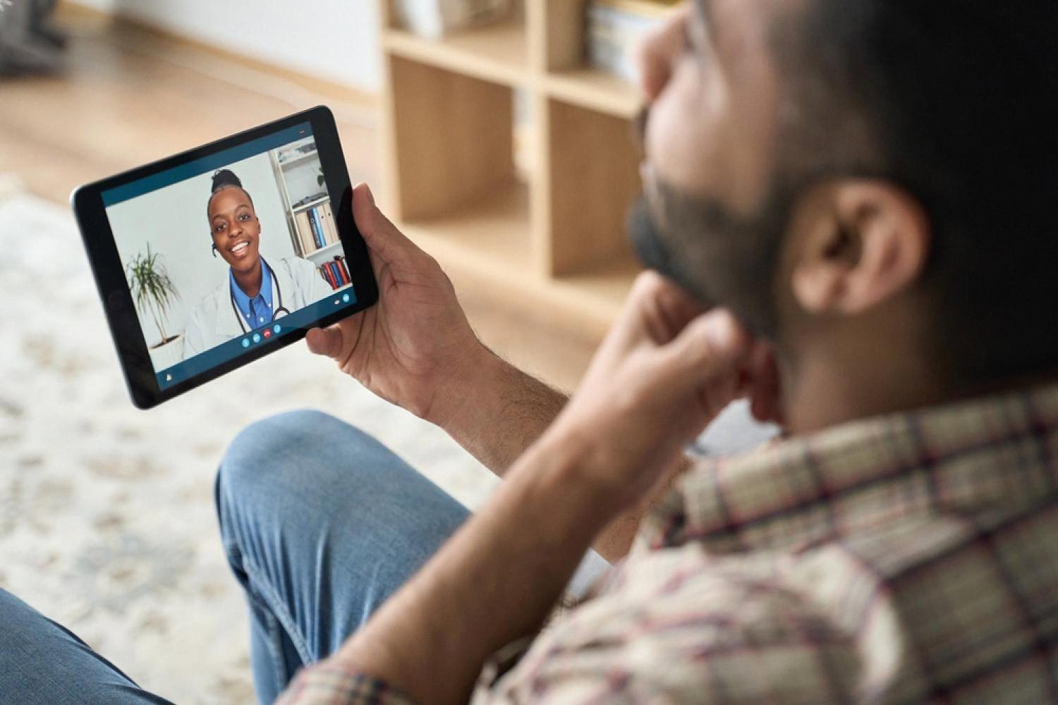 Man watching an online medical lesson with a doctor on a tablet screen