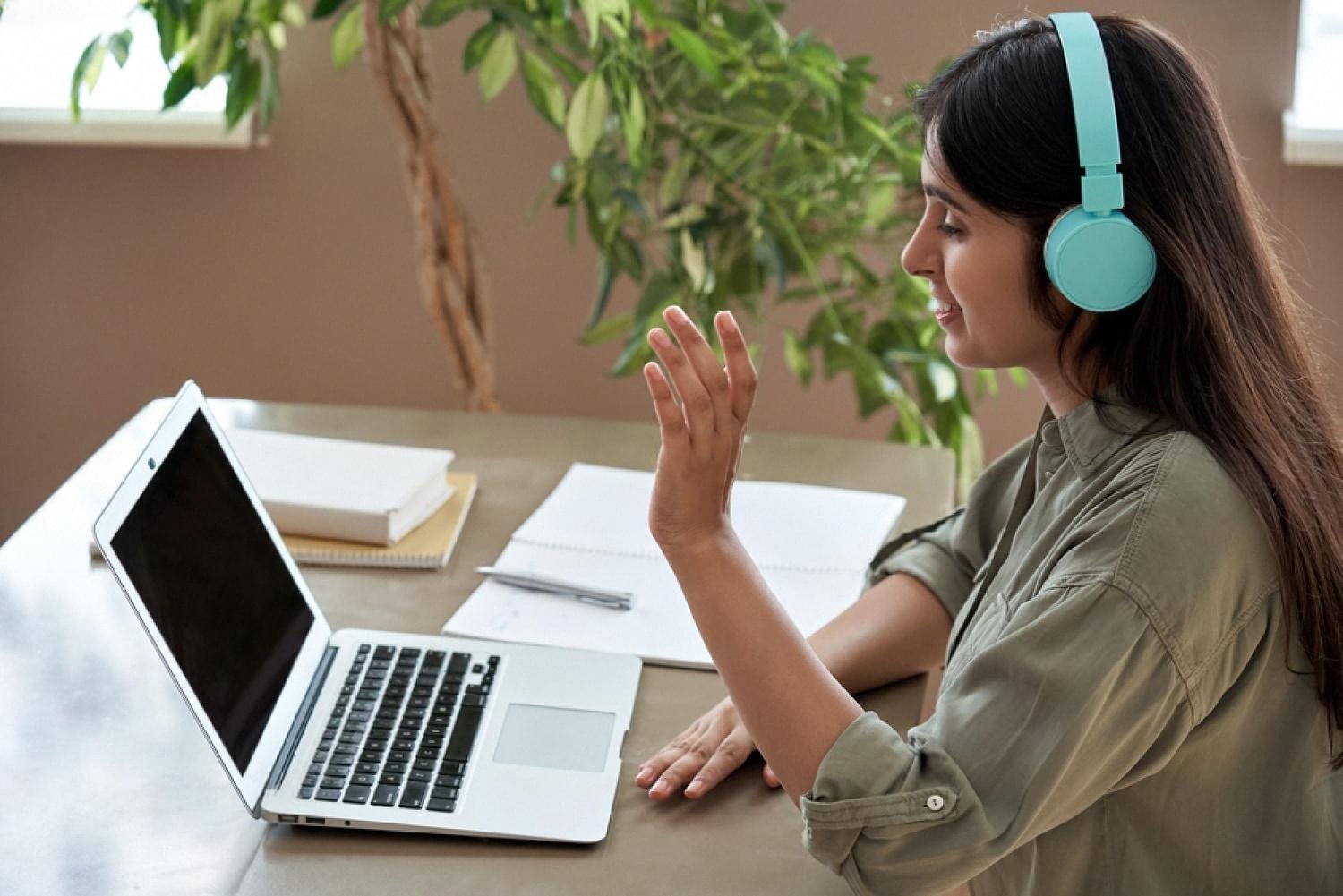 Woman in headphones talking during an online lesson on her laptop
